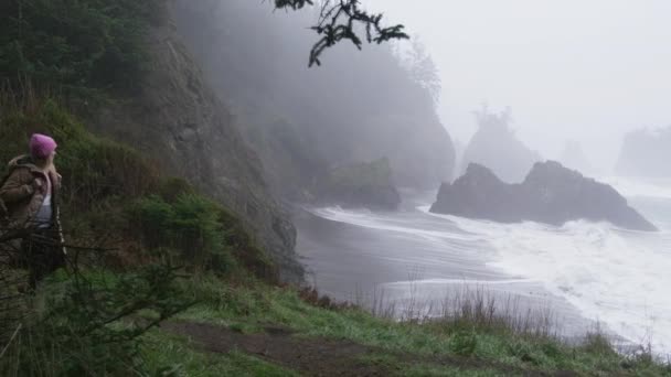 Glückliche Wanderin genießt ruhigen Regentag an der felsigen Küste von Oregon, ROTE Kameraaufnahme — Stockvideo