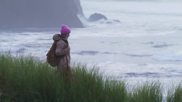 Slow motion RED camera shot with woman at scenic rocks in stormy ocean shore 6K — ストック動画