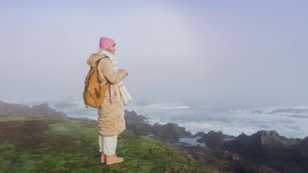 Slow motion shot op ROOD camera reiziger vrouw bij oceaan kliffen op mistige ochtend — Stockvideo