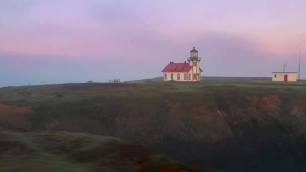 Beautiful aerial lighthouse with pink clouds colored by morning sunrise light 4K — Vídeo de Stock