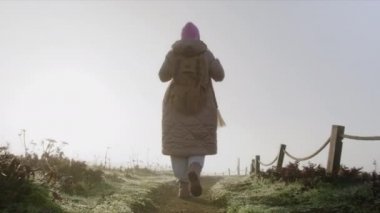 Slow motion traveler woman in coat with backpack enjoying sunny early morning 6K