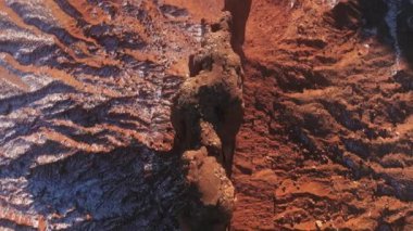 Top down narrow and tall red cliffs rising high at red desert covered by snow 