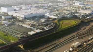 4K aerial footage of race track with brand new car driving to test, EV factory