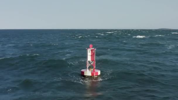 Aerial view of the buoy within the bluish sea waves and autumn forest behind — Stock Video