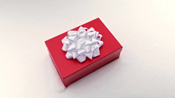 Большая красная коробка с большим белым бантом на белом снежном фоне — стоковое видео