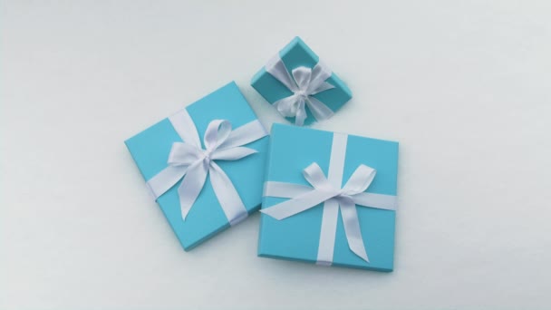 Beautiful teal blue boxes with white satin ribbon simple bows on snow background — Stock Video