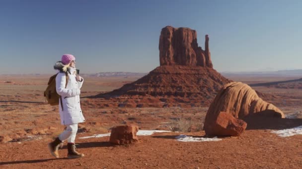 Câmera seguinte fêmea de casaco branco com mochila andando pela natureza vermelha do deserto — Vídeo de Stock