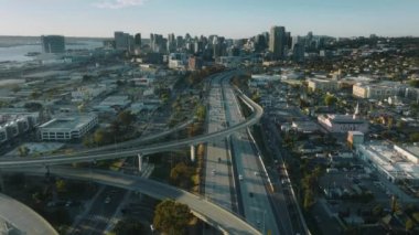 Gün batımında San Diego şehir merkezindeki sinemada. Güneşli bir yaz gününde yoğun otoyolun üzerinde modern binalara doğru uçan insansız hava aracı. Amerikan şehir arkaplanı, konut binaları, California USA 4K