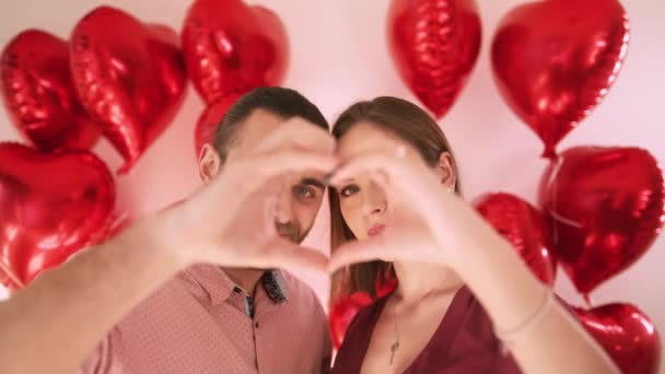 Happy beautiful young woman and handsome man making heart shape hand gesture — Stock Video