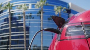 Yavaş çekim tanınmayan işadamı kırmızı elektrikli cipten şarj aleti çekiyor.