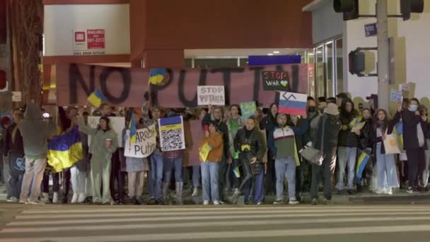Des rues nocturnes remplies de manifestants militants défilant avec des bannières NO WAR — Video