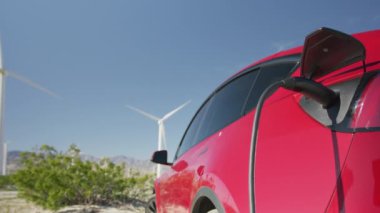 İstasyonda rüzgar türbinleriyle yüklü jenerik elektrikli araba.