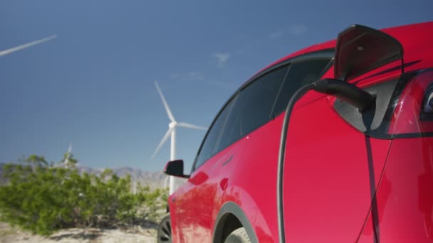 Primo piano al rallentatore del caricabatterie per auto elettriche nella soleggiata giornata estiva in movimento mulini a vento — Video Stock