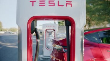 Beyaz ve kırmızı Tesla otonom elektrikli arabalar enerjiyi hızlı şarj ederek dolduruyorlar