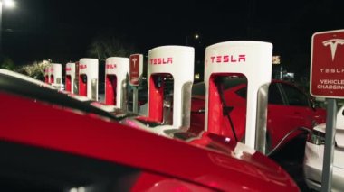 Tesla hafif elektrikli otomobiller şarj istasyonundaki bataryaları doldurur, kırmızı kamera 6K