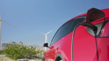 İstasyonda rüzgar türbinleriyle yüklü jenerik elektrikli araba.