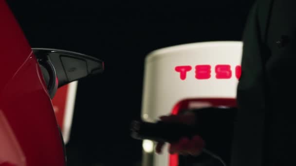 Mujer de negocios desconecta el cable de carga en el vehículo eléctrico Tesla, cámara RED — Vídeo de stock