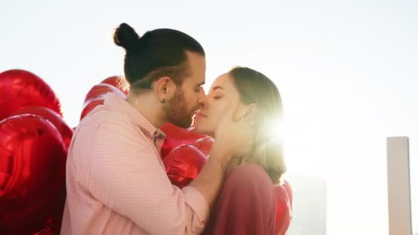 Νεαρό όμορφο hipster ζευγάρι φιλιά στο γραφικό χρυσό ηλιοβασίλεμα με κόκκινα μπαλόνια — Αρχείο Βίντεο