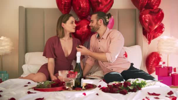 Amante macho alimentação bela mulher sentados juntos na cama em hotel decorado — Vídeo de Stock