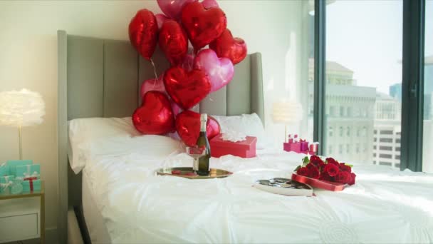 Hermosas rosas rojas y globos de corazón en la cama, sorpresa romántica en la habitación del hotel — Vídeos de Stock