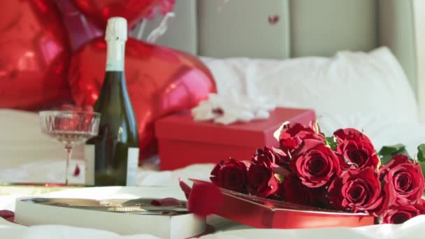 Лепестки роз падают на белую кровать в замедленной съемке, крупным планом на красную камеру — стоковое видео