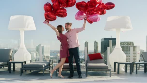 Ημέρα του Αγίου Βαλεντίνου ευτυχισμένη νεαρή γυναίκα και ο άνθρωπος κρατώντας δέσμες από μπαλόνια κόκκινη καρδιά — Αρχείο Βίντεο