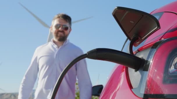 Schöner, stilvoller, reifer Mann zieht Ladekabel aus Elektrofahrzeug, 6K — Stockvideo