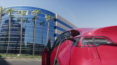 Kadın elektrikli aracının fişini çekmek için arabadan çıkıyor, Dolly.