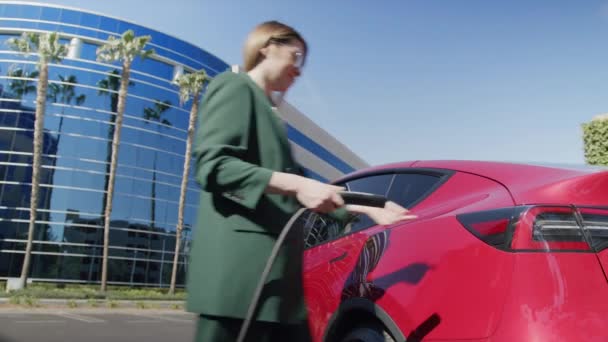 Klasik takım elbiseli başarılı bir kadın iş yerindeki elektrikli araca yürüyor. — Stok video