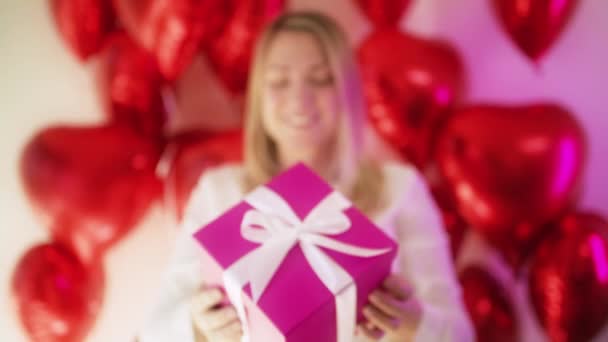 Jeune femme excitée client montrant lumineux rose magenta boîte cadeau ruban blanc — Video
