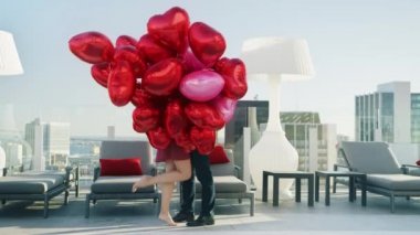 Güzel bir çift çatıda romantik bir randevuya çıkıyor, Aşıklar kırmızı balonlarla öpüşüyor.