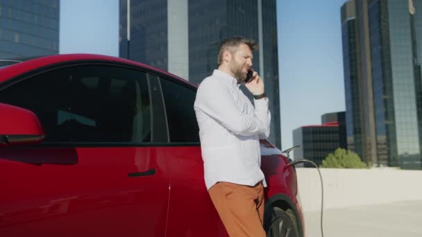 Rode SUV elektrische auto aangesloten op laadstation in de stedelijke binnenstad achtergrond 4K — Stockvideo