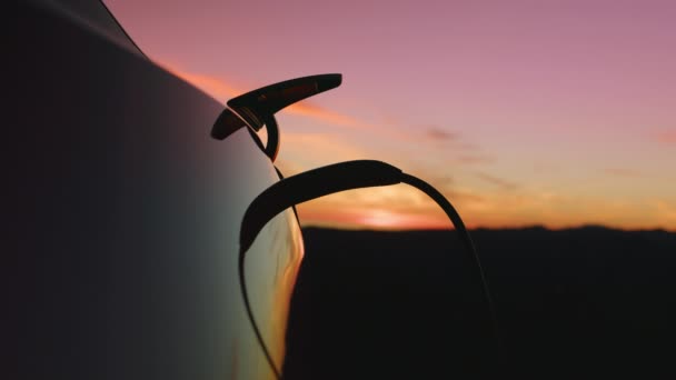 Közelkép férfi töltés elektromos EV autó szabadban az arany napfény, piros kamera — Stock videók