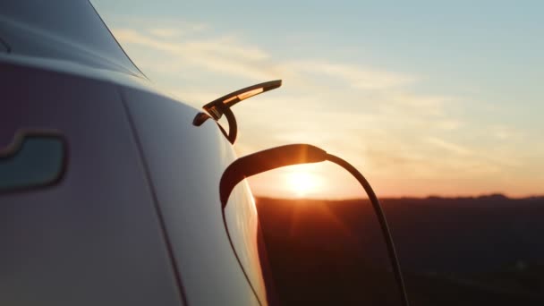 Modern yenilikçi SUV aracı elektrikli araç şarj oluyor. Manzaralı gün batımı. — Stok video