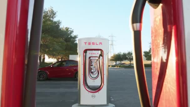 Tesla Model Y vozidlo nabíjení na Tesla super nabíječka elektrické venkovní při západu slunce — Stock video