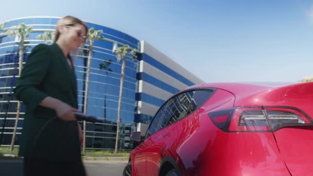Mooie jonge professionele vrouw pluggen in oplaadsnoer bij elektrische auto — Stockvideo