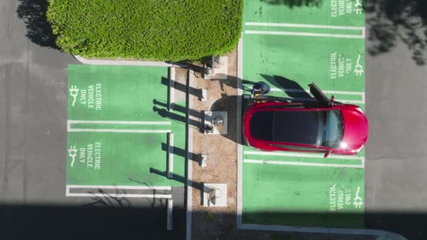 EV környezetbarát elektromos autók, drónlövés ember felett kihúzható töltővezeték — Stock videók