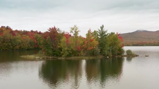 Cinematic air island in mountain lake, Vermont peak season foliage background — Stock video