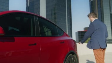 Akıllı yetişkin iş adamı pili şarj etmek için elektrikli araca kablo bağlıyor