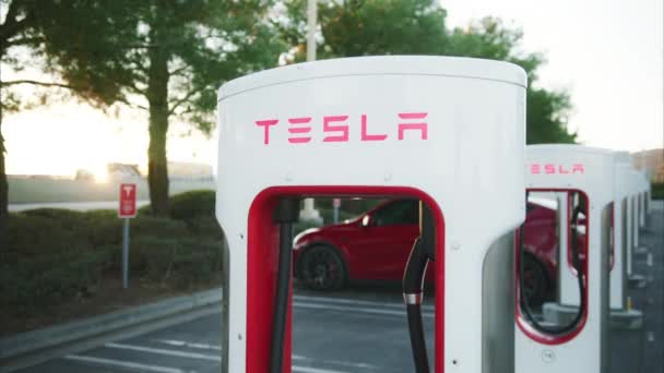 Tesla laddningsbatteri för elbilar vid superladdare på cinematisk gyllene solnedgång — Stockvideo