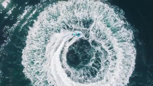 Powietrzne epickie ujęcie człowieka na skuterze wodnym ścigającego się po głębokiej błękitnej, zielonej, czystej wodzie morskiej 4K — Wideo stockowe
