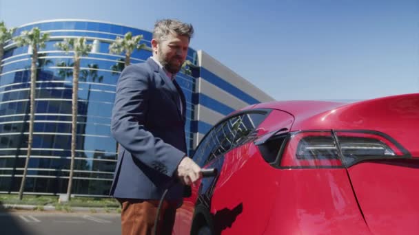 Dolly rood schot van de blanke man in blauw pak werken bij het opladen van elektrische auto — Stockvideo