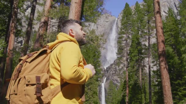 Stilig manlig resenär med ryggsäck vid Yosemite vattenfall, i nationalpark — Stockvideo