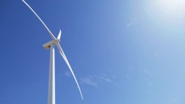 Temiz mavi gökyüzü arka planında, güneşli ve parlak 6K ABD 'li sinematik yel değirmenleri