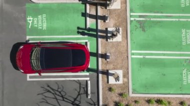 İnsansız hava aracı, modern kırmızı elektrikli aracın üzerinde yükseliyor.