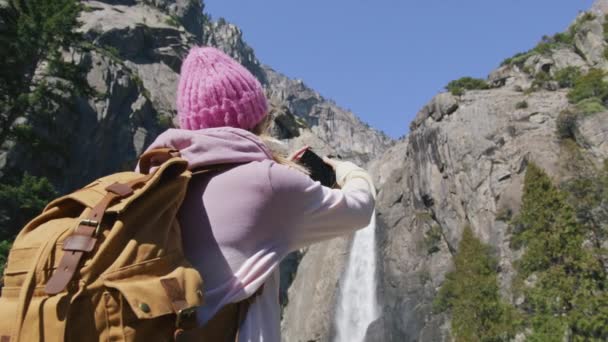 美丽的旅行者或博客写手在风景秀丽的高山山谷与瀑布 — 图库视频影像