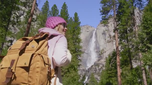 慢动作的年轻女旅行家带着约塞米蒂瀑布的景色在森林里徒步旅行 — 图库视频影像
