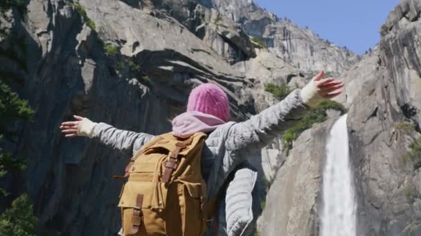 Mladá žena s turistickým batohem při pohledu na malebný vodopád na vrcholu hory — Stock video