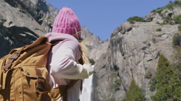 Freie glückliche Wanderin mit Touristenrucksack, die zum Yosemite-Wasserfall aufschaut — Stockvideo