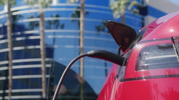 Jóképű férfi kinyitja az ajtót, kiszáll az autóból, hogy kihúzza a töltőkábelt a 6K járműből. — Stock videók